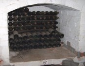 The photograph shows a brick-built bay in the cellars at Camden Park, containing old bottles of red wine from the 19th century.